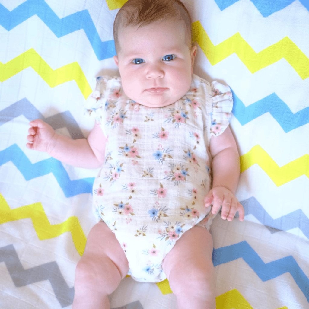 A baby is lying down on a Bebekish Bamboo Muslin Swaddle 
