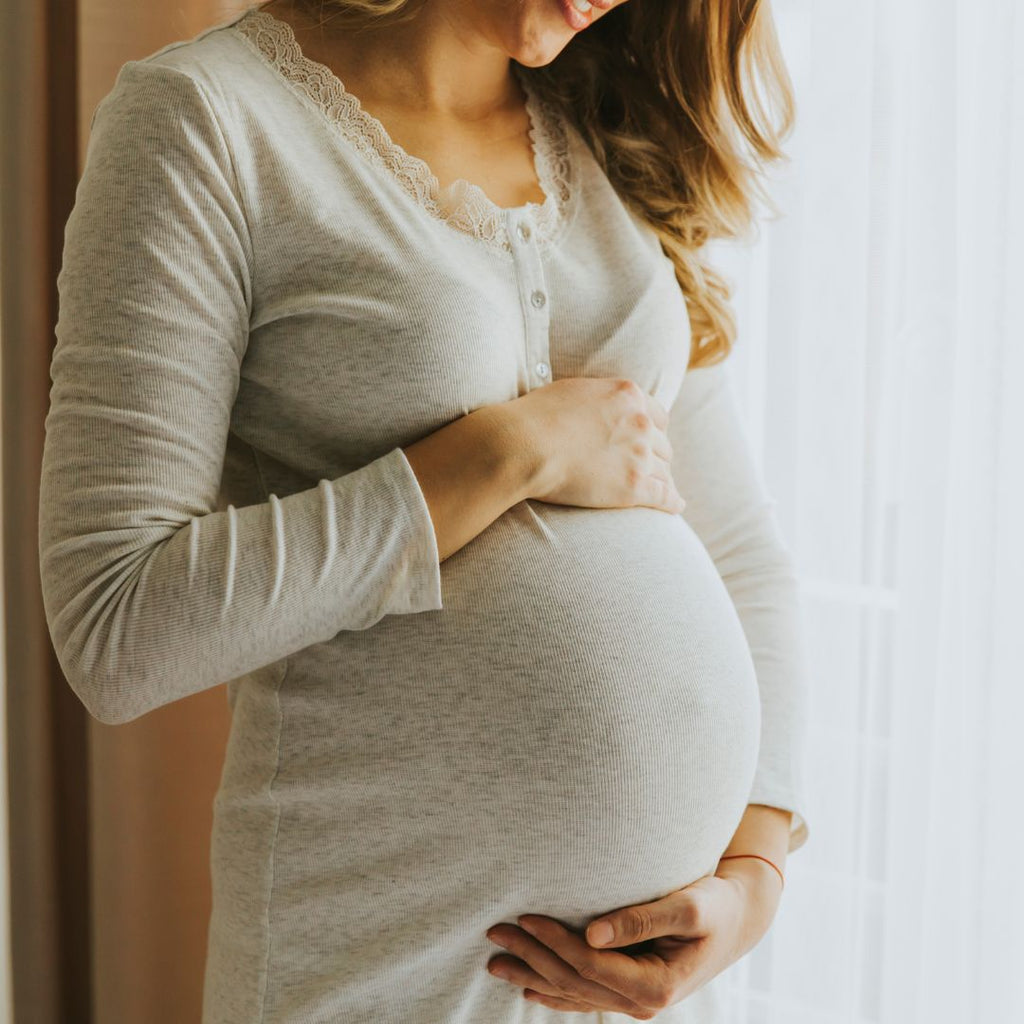 a pregnant woman standing by the window